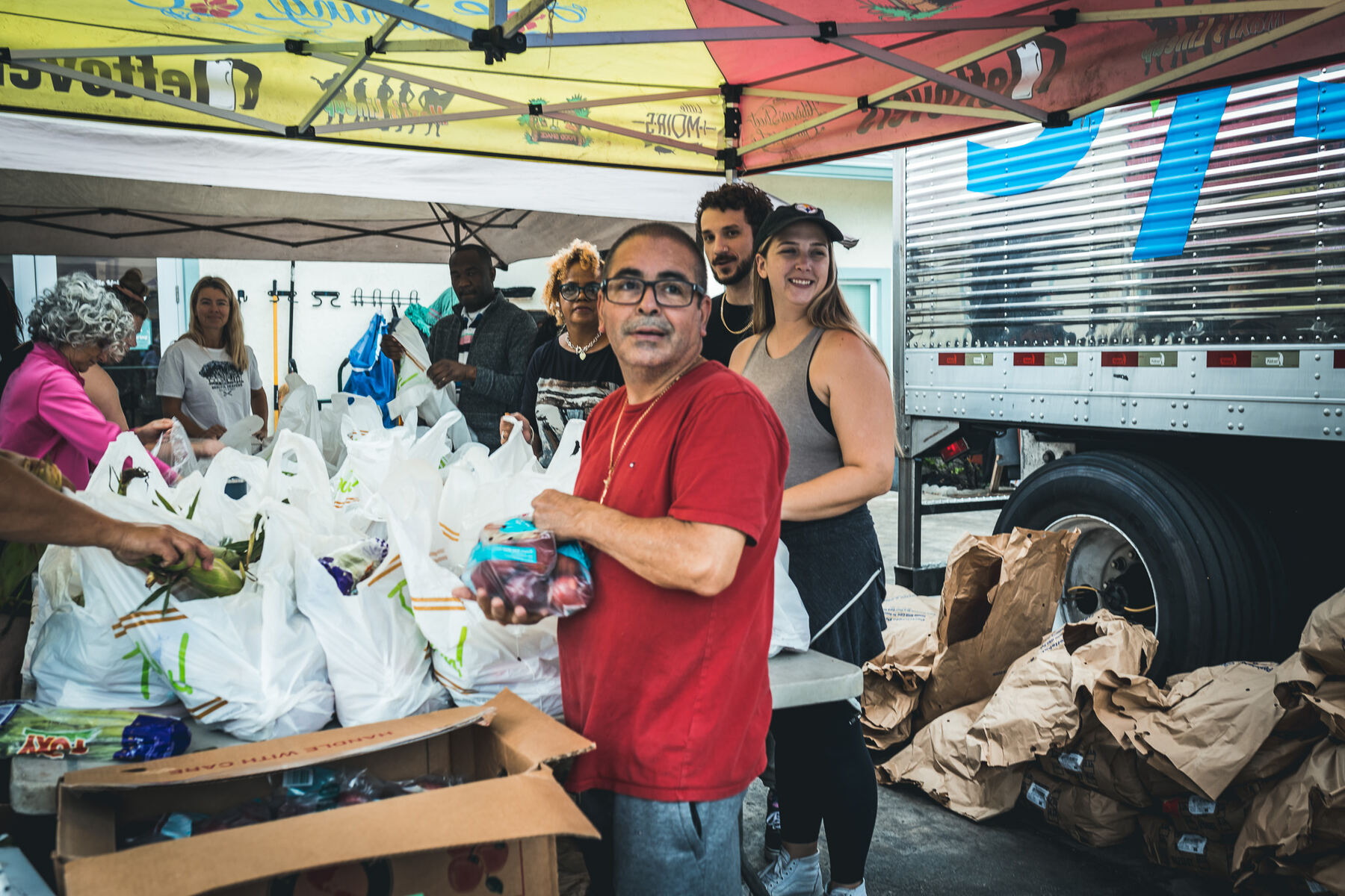 Merciful Heavens volunteers smiling behind bags of packed Thanksgiving groceries