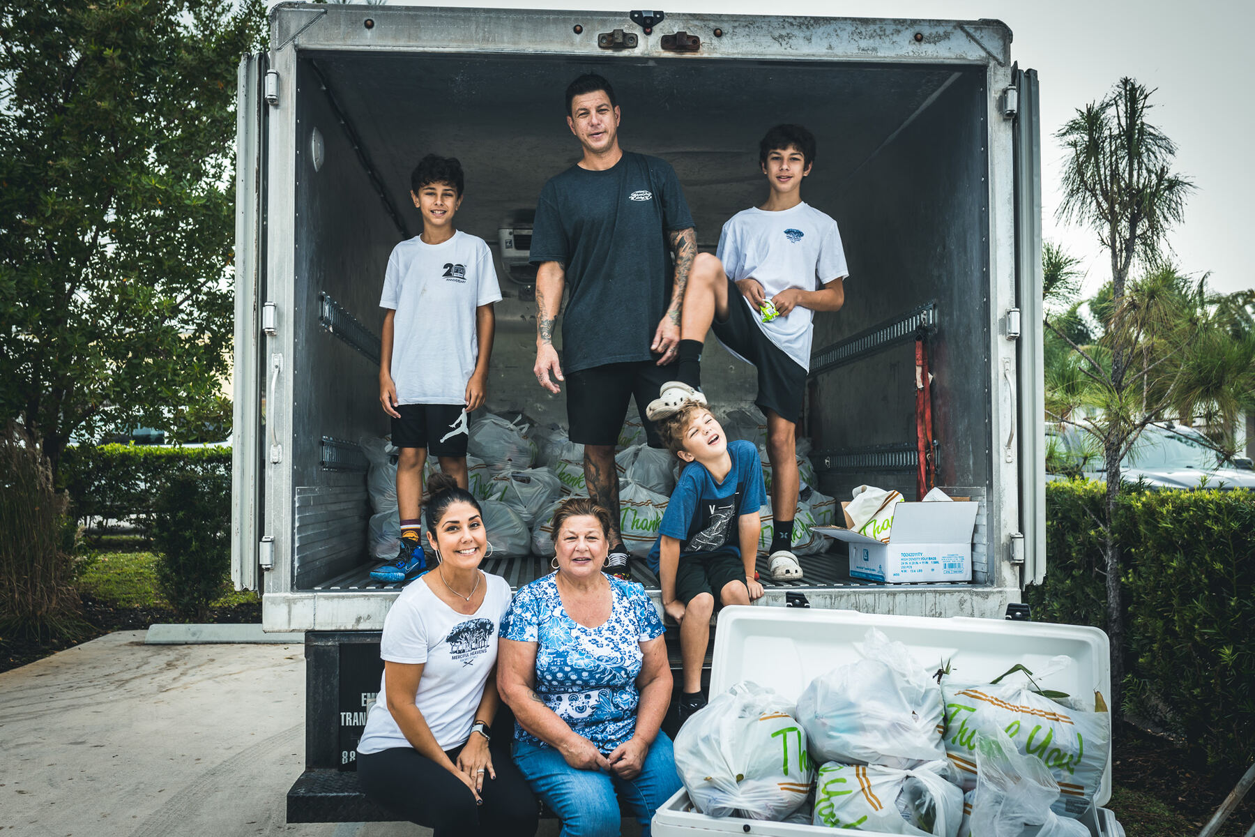Family of volunteers posing in the delivery truck full of bags