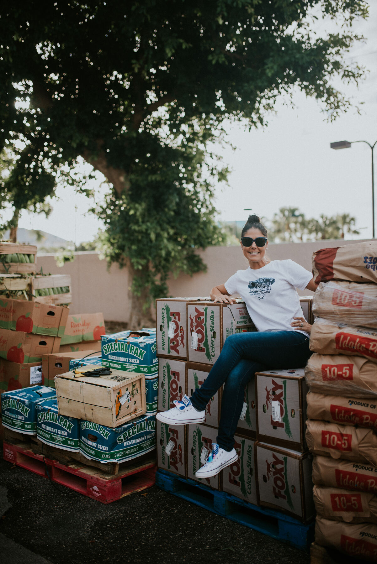 Volunteer sitting on stacked crates of donated produce