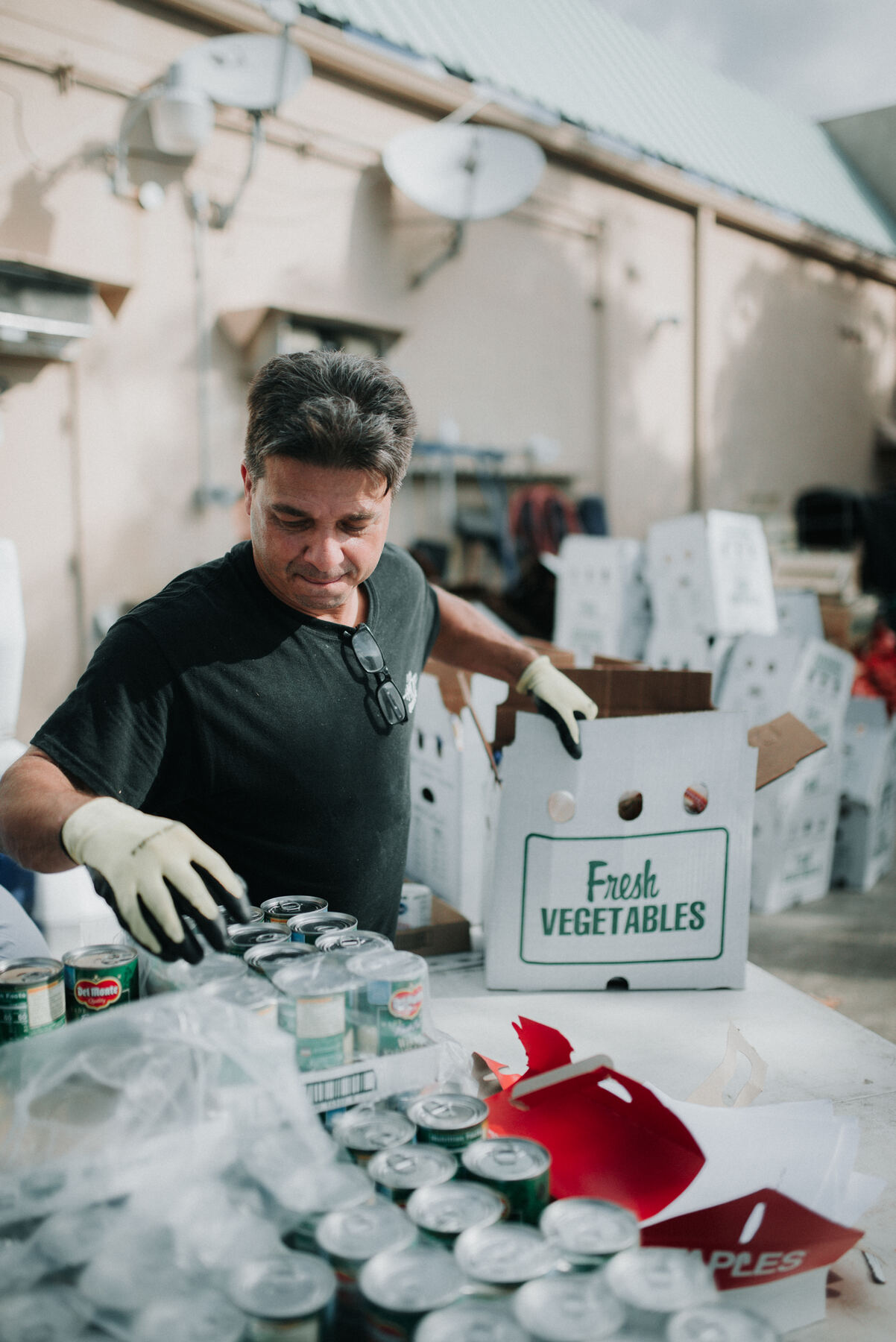 Volunteer packing a Fresh Vegetables box with canned goods